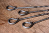 A set of hand forged Skewer handles on a wooden surface by Wicks Forge