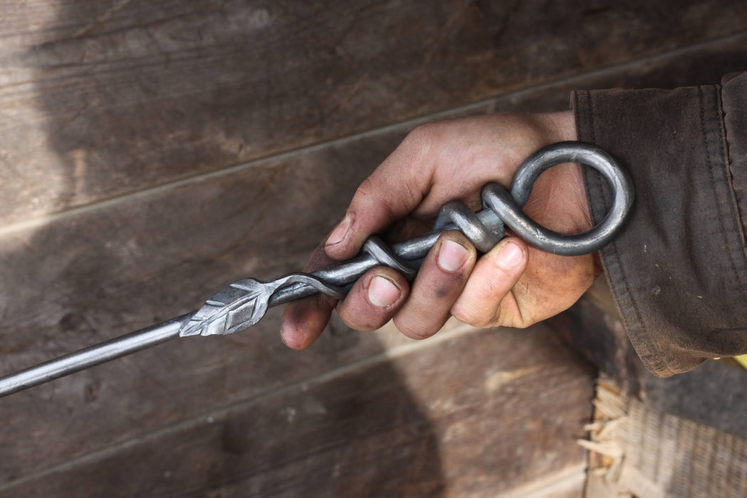 a blacksmith hand forged fire poker with a leaf wrap design by Wicks Forge