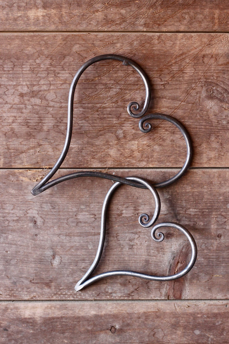 a pair of blacksmith hand forged linked hearts by Wicks Forge