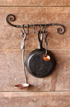 a blacksmith hand forged pot and pan holder with a scrolled design by Wicks Forge